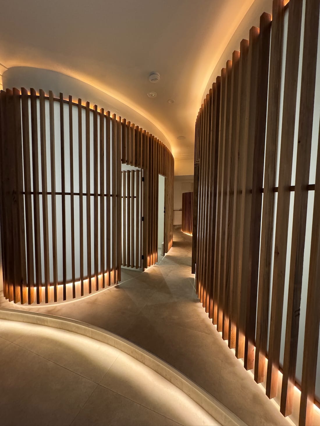 A warm-lit corridor between curved timber walls