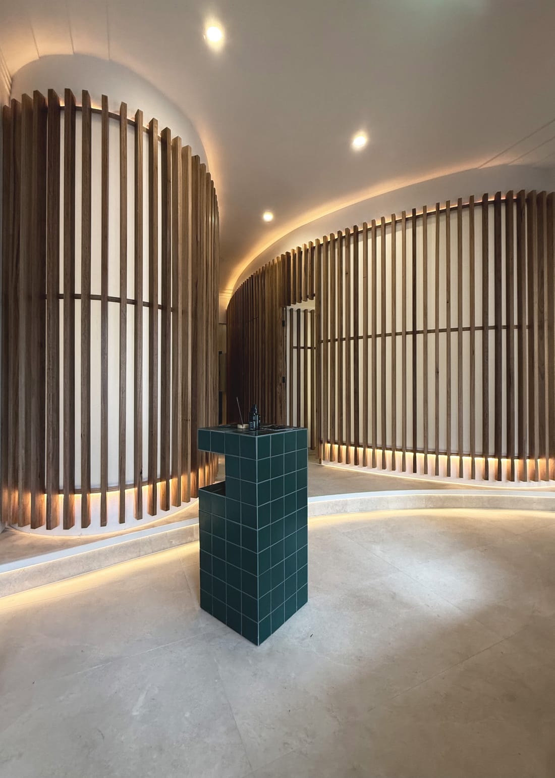 The curved timber slat hall with a green tiled plinth