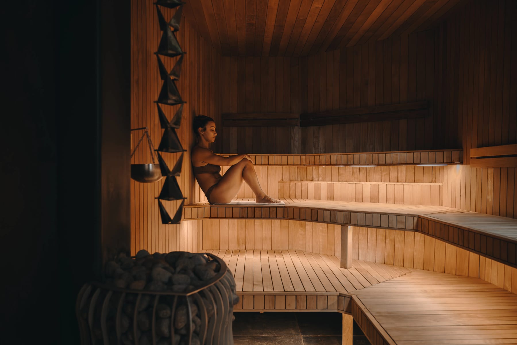 A lone bather on the glowing timber benches of the hot rock sauna