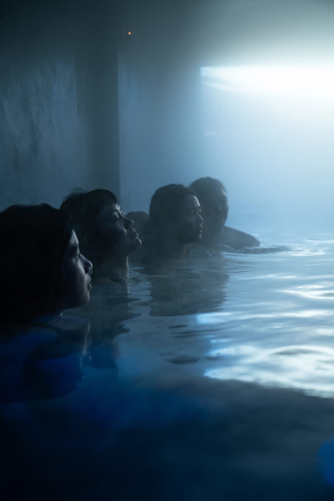 Bathers in the misty pool, lit by a beam of light