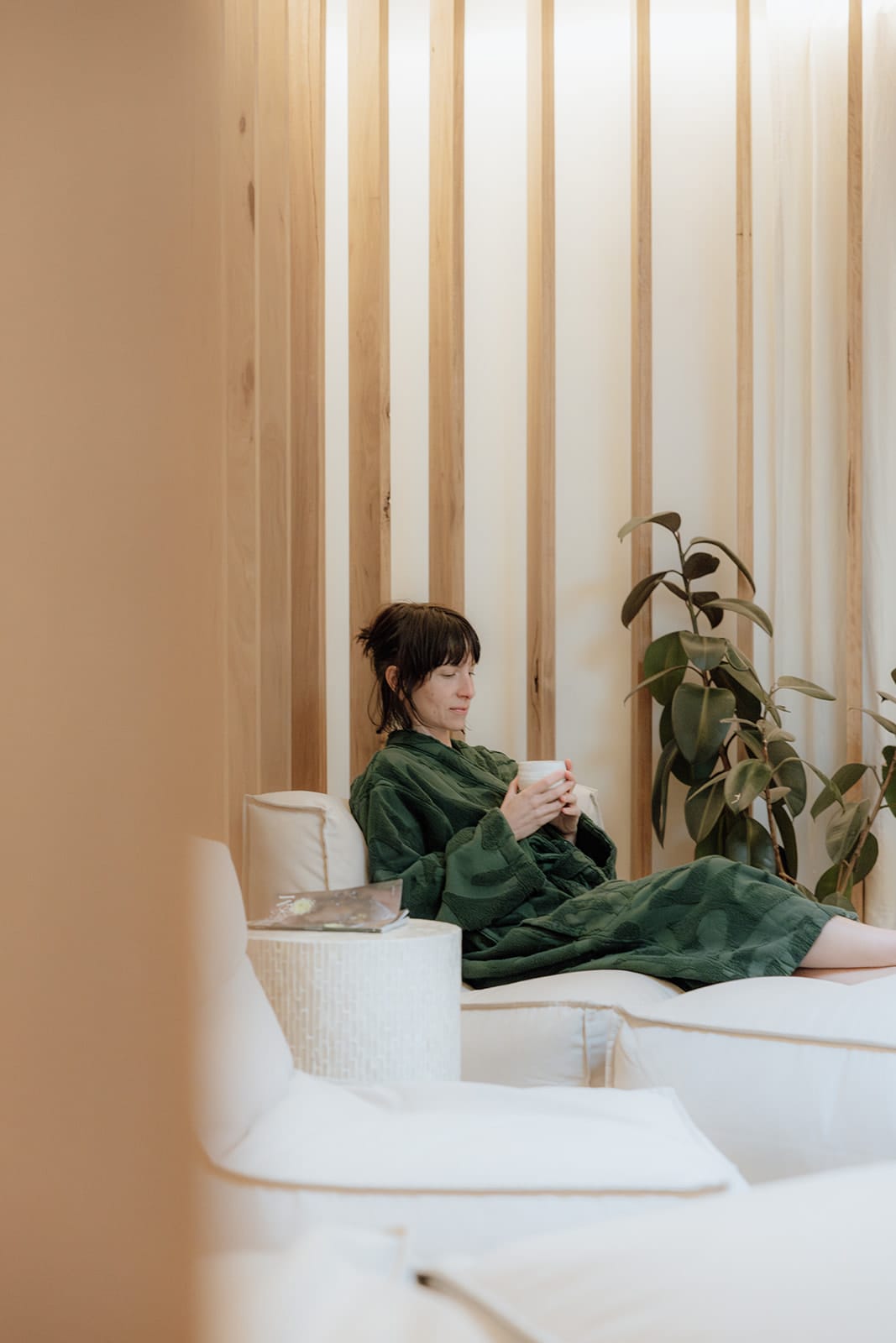 A guest in a green robe with a cup of tea in the lounge